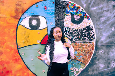 Portrait of smiling young woman standing against graffiti