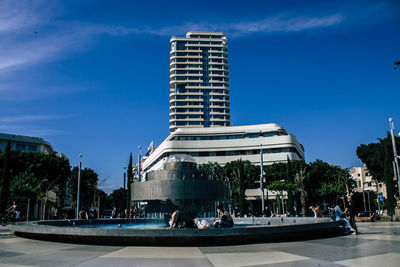 People sitting by pool and fountain