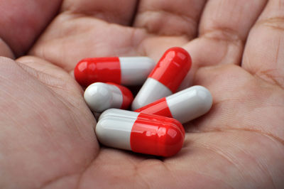 Close-up of hand holding red capsules