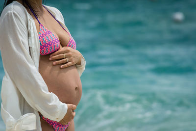 Midsection of woman standing against sea