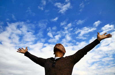 Low angle view of man gesturing against sky