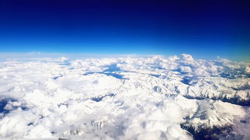 Aerial view of snow covered landscape against blue sky