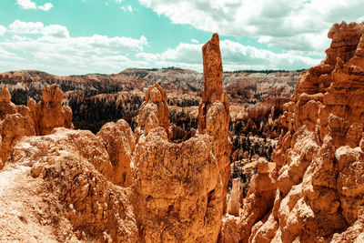 Rock formations on landscape against cloudy sky