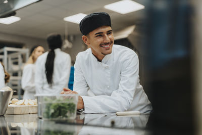 Smiling male trainee leaning on kitchen counter