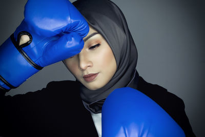 Close-up portrait of young woman against blue background