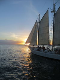 Sailboat sailing on sea against sky during sunset