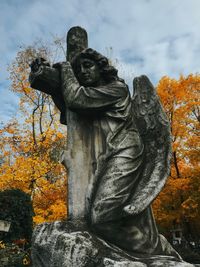 Low angle view of angel statue against sky during autumn