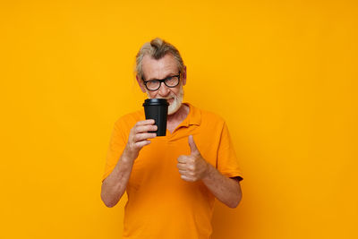 Portrait of senior man against yellow background