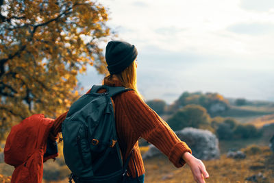 Rear view of woman with umbrella against sky during autumn