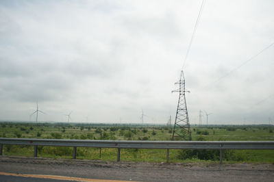 Electricity pylons on field against sky