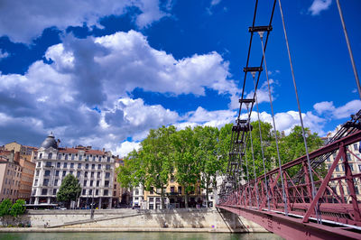 View of road by buildings against cloudy sky