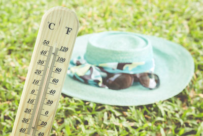 Close-up of thermometer against hat on field