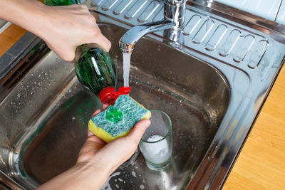 Midsection of woman pouring water in kitchen at home