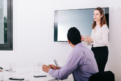 Businesswoman explaining while coworker sitting by conference table