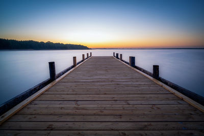 Wooden pier over lake against sky during sunset