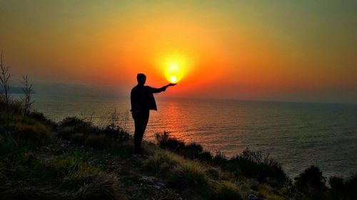 Silhouette man standing on beach during sunset