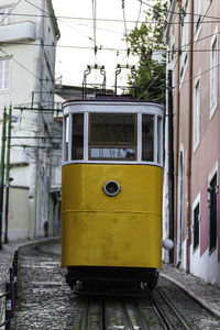 Yellow train on railroad track in city