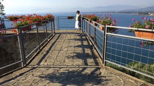 People standing by railing against sea