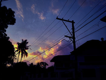 Low angle view of silhouette electricity pylon against sky at sunset