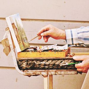 Cropped image of painter painting against wall