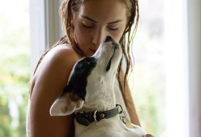 Close-up of young woman with dog by window