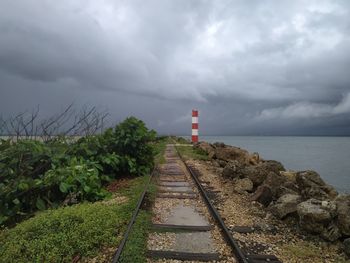 Lighthouse amidst railroad tracks against sky