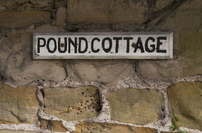 Sign board with text mounted on stone wall at cottage