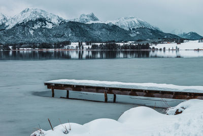 The hopfensee with the allgäu alps in winter. germany. in the foreground snow-covered jetty.