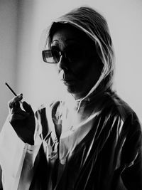 Woman wearing raincoat and sunglasses while smoking cigarette