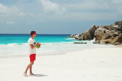 Full length of man standing at beach against sky during summer