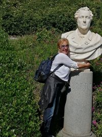 Statue of woman standing by plants