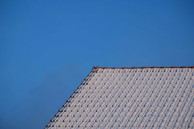 Low angle view of building roof against clear blue sky