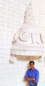 Portrait of a smiling young man standing against wall