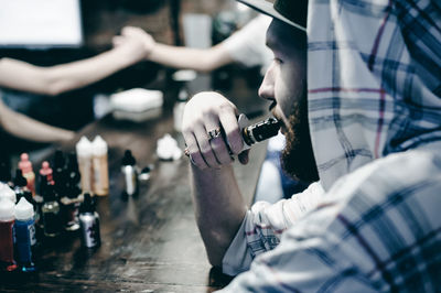 Close-up of young man smoking electronic cigarette at table