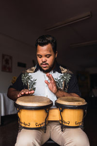 Black male musician in casual clothes sitting on chair with drums