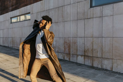 Side view of young man looking away against wall