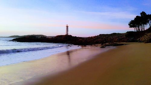 View of lighthouse at beach during sunset