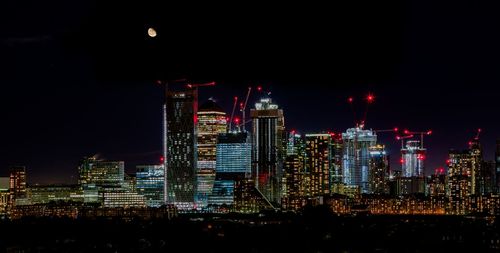 Illuminated buildings in city against sky at night