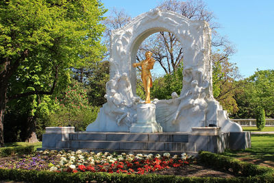 Statue by fountain against trees in park