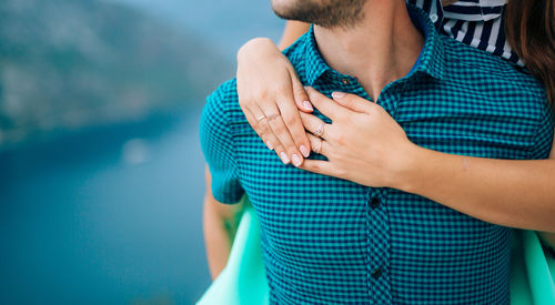 Midsection of man and woman standing against blue wall