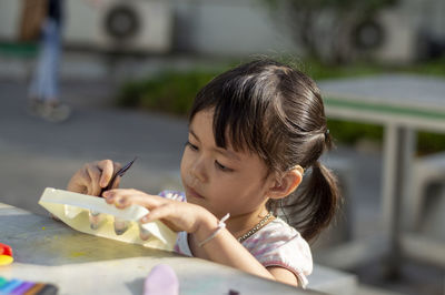 Close-up of cute girl playing with childs play clay at table outdoors