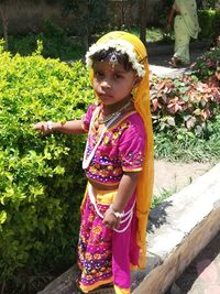 Full length of cute girl standing against plants with lord radha's makeup