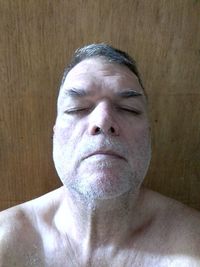 Close-up portrait of shirtless man against wall