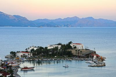 Sailboats moored in sea against sky during sunset