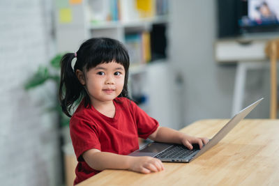 Portrait of young woman using laptop at home