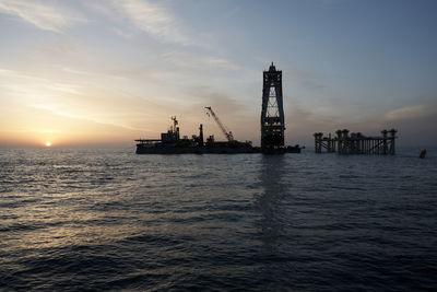 Silhouette ship in sea against sky during sunset