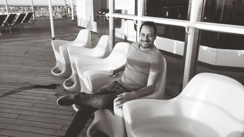 Full length portrait of smiling man on seat in cruise ship