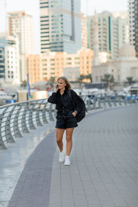 A young woman with a smartphone is standing on the embankment. the concept of online communication