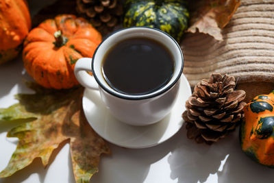 Autumn, fall leaves, hot steaming cup of coffee and a warm scarf on white table background