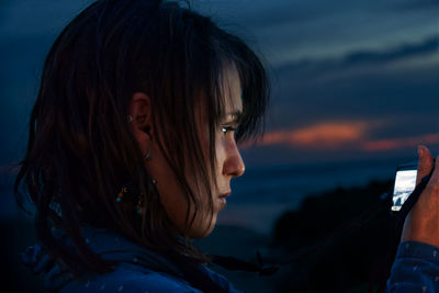 Close-up of young woman photographing using camera at sunset